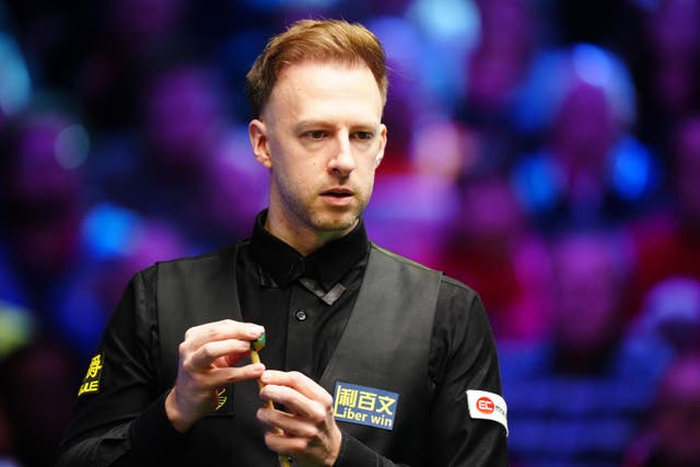 Judd Trump looks at the table as he chalks his cue