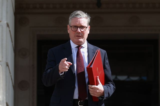 Sir Keir Starmer pointing and holding a red folder as he leaves Parliament Buildings at Stormont