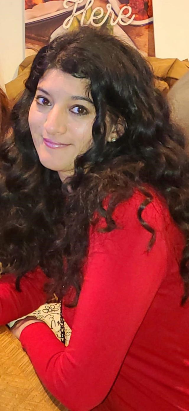 Zara Aleena, wearing a red top and smiling at the camera.