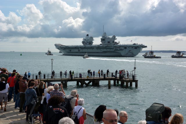 Families and well-wishers wave off Royal Navy aircraft carrier HMS Prince of Wales as it leaves Portsmouth Naval Base
