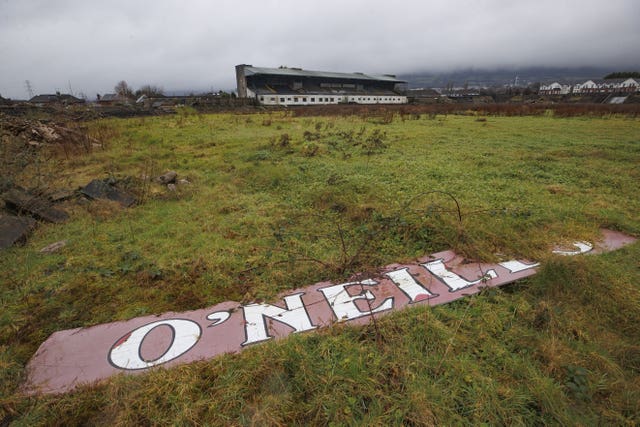 Original wooden O’Neills advertising board with grass and moss growing on top of the over grown pitch at Casement Park