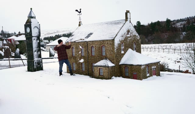 Lawson Robinson clears snow from his Nenthead miniature village in Cumbria 