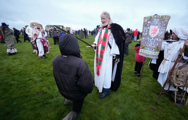 Arthur Pendragon ‘knights’ a member of the public as they take part in the winter solstice celebrations during sunrise at Stonehenge