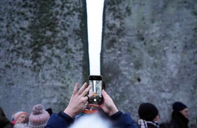 A person takes a photograph of the stones as they take part in the winter solstice celebrations during sunrise at Stonehenge 