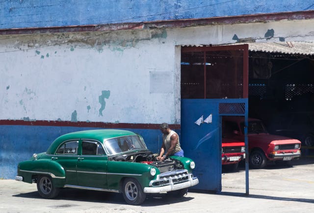 A vintage American car is fixed by the roadside in Old Havana, Cuba (Jane Barlow/PA)
