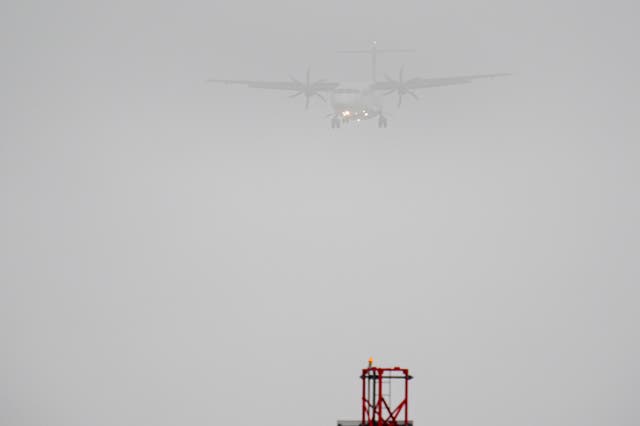 A plane lands in the mist at Cardiff Airport