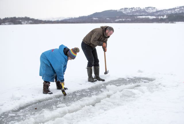 Al and Alice Goodridge, from Newtonmore, use a sledgehammer and an axe to create a channel in the ice in Loch Insh, in the Cairngorms National Park, for Alice to swim in 