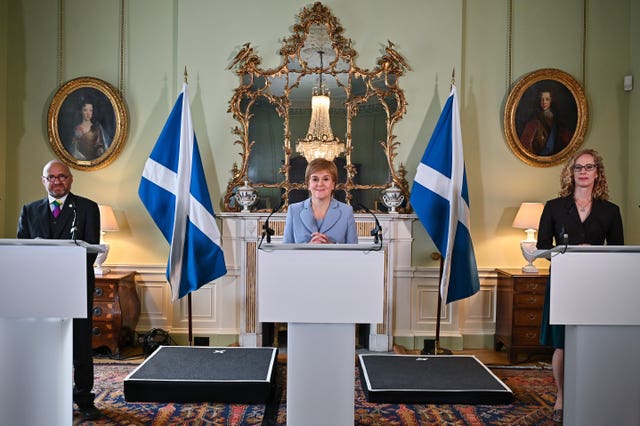 Nicola Sturgeon speaking from a podium, flanked by Patrick Harvie and Lorna Slater