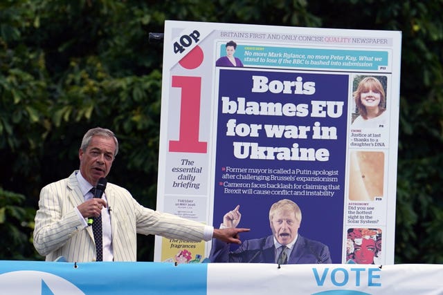 Nigel Farage speaking into a microphone on top of an open top bus alongside a poster showing a 2016 front page of the i newspaper with the headline 'Boris blames EU for war in Ukraine'