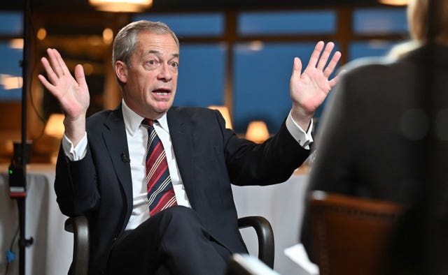 Nigel Farage raises his hands during an interview