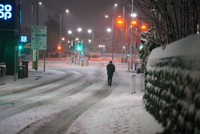 A person walks along a snow covered street 