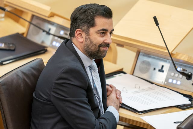 Humza Yousaf smiles while sitting in the Scottish Parliament