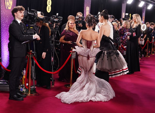 The singers from KPop Demon Hunters speak to the media line with their backs to the camera