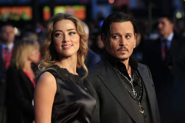 Amber Heard smiling while standing next to Johnny Depp at a red carpet event