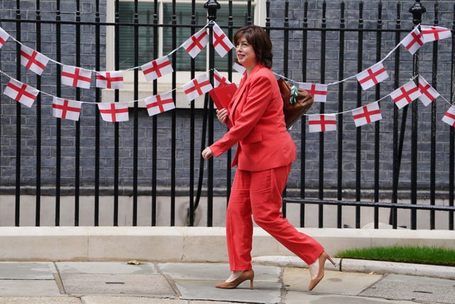 Commons Leader Lucy Powell wearing red in Downing Street, in front of England flag bunting