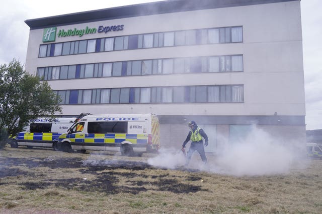 A police officer extinguishing a fire during an anti-immigration demonstration outside the Holiday Inn Express in Rotherham