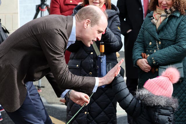 William has a high five with young fan Florence Boyle during his visit to The Turf 