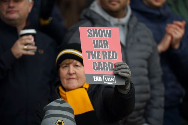 A Wolves fan holds up a red card protesting against the use of VAR