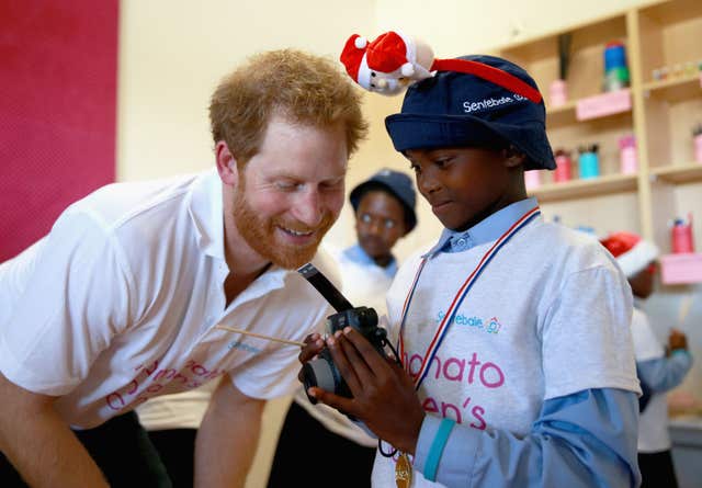 Harry helps a boy during a photography activity