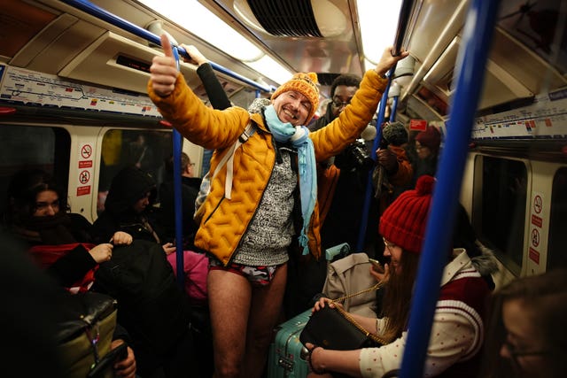 Man dressed in orange puffer jacket an multicoloured knickers while on the Tube