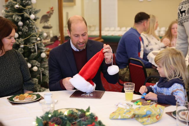 William holds a santa hat as he sits at a table with military families at Picton Barracks in Bulford, Wiltshire 