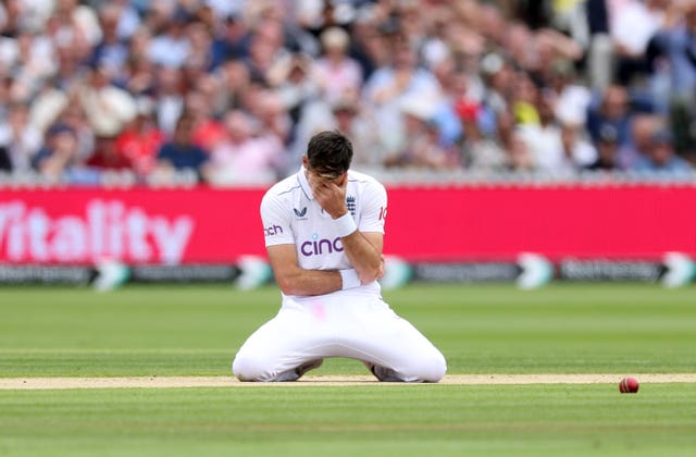James Anderson hangs his head as he kneels on the ground after dropping a caught and bowled chance. 