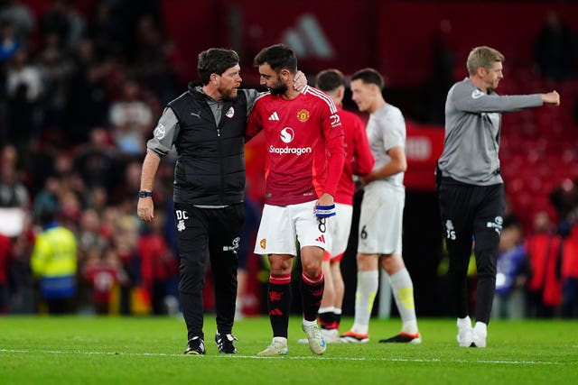 Barnsley manager Darrell Clarke, left, puts his arm around Manchester United midfielder Bruno Fernandes