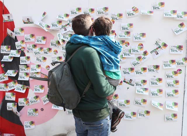 A father and son look at sympathy messages left at the mural. (Niall Carson/PA)
