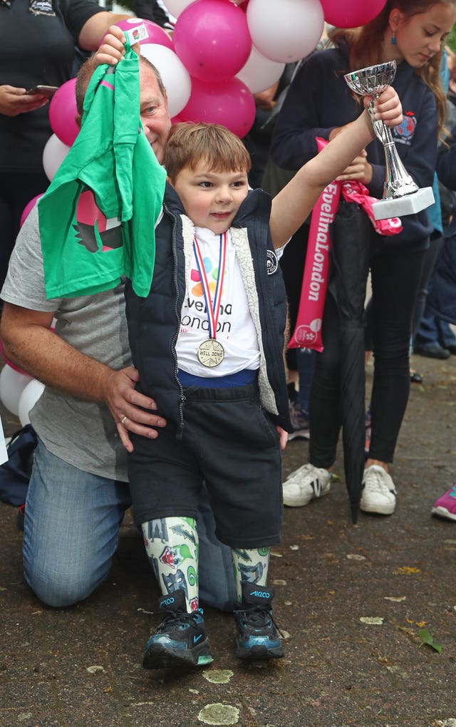 Tony Hudgell, who uses prosthetic legs, celebrates after taking the final steps in his fundraising walk in West Malling, Kent 