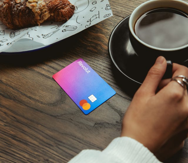 A Revolut card on a table next to a coffee and pastry