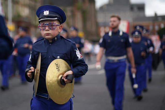 A boy marches with cymbals through Belfast in uniform 