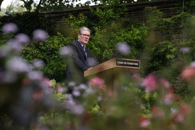 Flowers in the foreground as Sir Keir Starmer stands behind a podium delivering a speech in the rose garden at 10 Downing Street