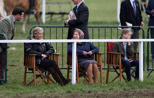 The Queen, looking delighted and wearing a headscarf, and Sophie sit in wooden director chairs on the edge of the course at the Royal Windsor Horse Show in 2015