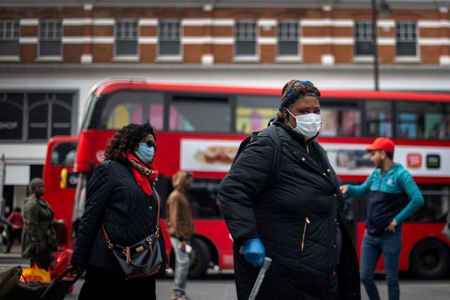 A woman in a protective face mask walks through Brixton Market in South London (Victoria Jones/PA)