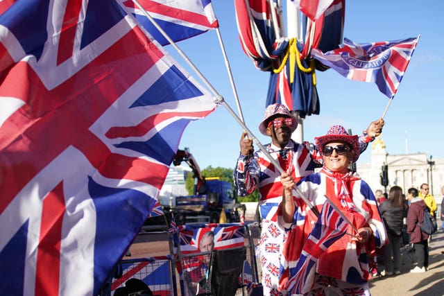 Royal fans dressed in Union flag themed suits wave Union flags on The Mall ahead of the Trooping the Colour ceremony