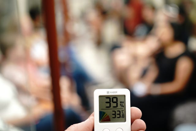 A person holds a thermometer on the Bakerloo line of the London underground