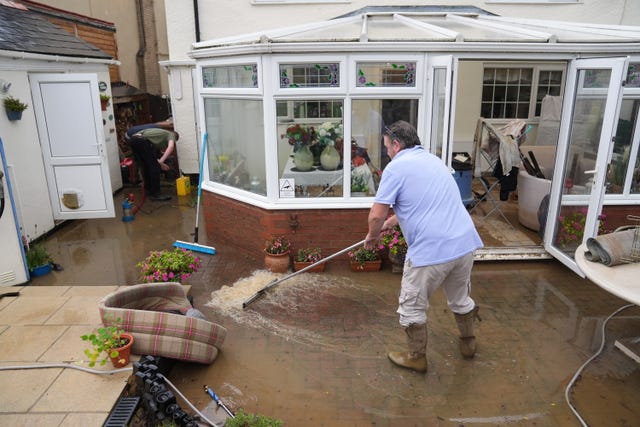 Neighbours help to clear flood water from the home of Jon Sayles in Grendon, Northamptonshire 