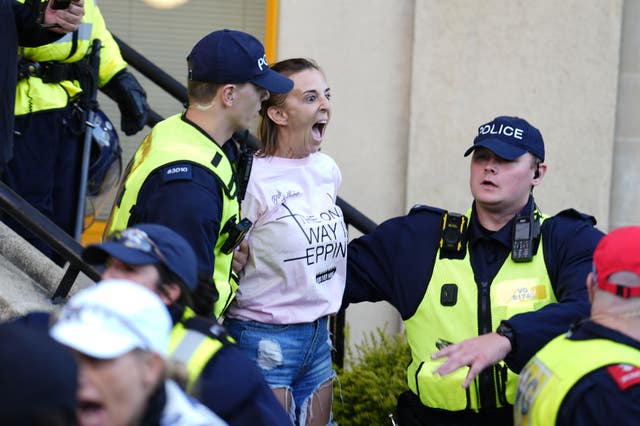 A protester is detained by police after hanging a Union flag from the civic offices, as protesters march in Epping, Essex