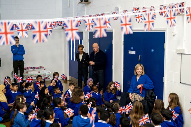 Ross Kemp and Dame Kelly Holmes speak to schoolchildren waving Union flags 