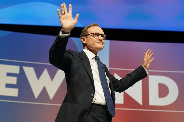 Tom Tugendhat raises his hands while delivering a speech at the Conservative Party conference