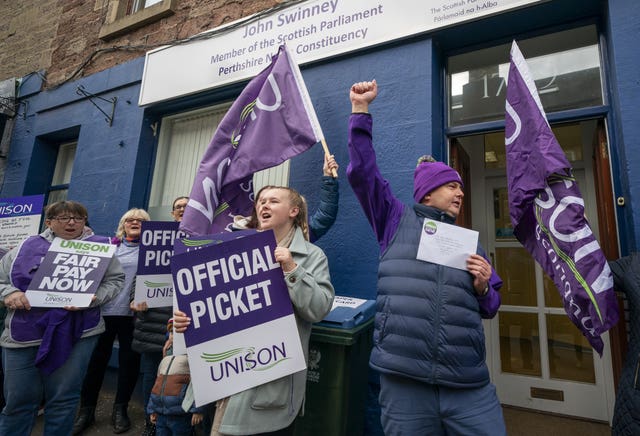 Unison picket line, with union members waving flags and raising their arms