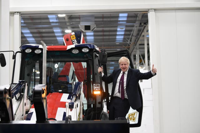 Prime Minister Boris Johnson gestures after driving a Union flag-themed JCB, with the words Get Brexit Done (Stefan Rousseau/PA)