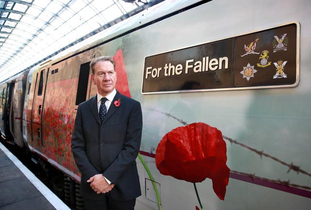 Michael Portillo next to a train featuring a poppy during a remembrance event for rail workers