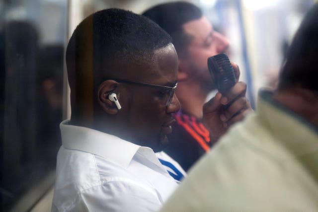 A man uses a fan on the London Underground's Piccadilly Line