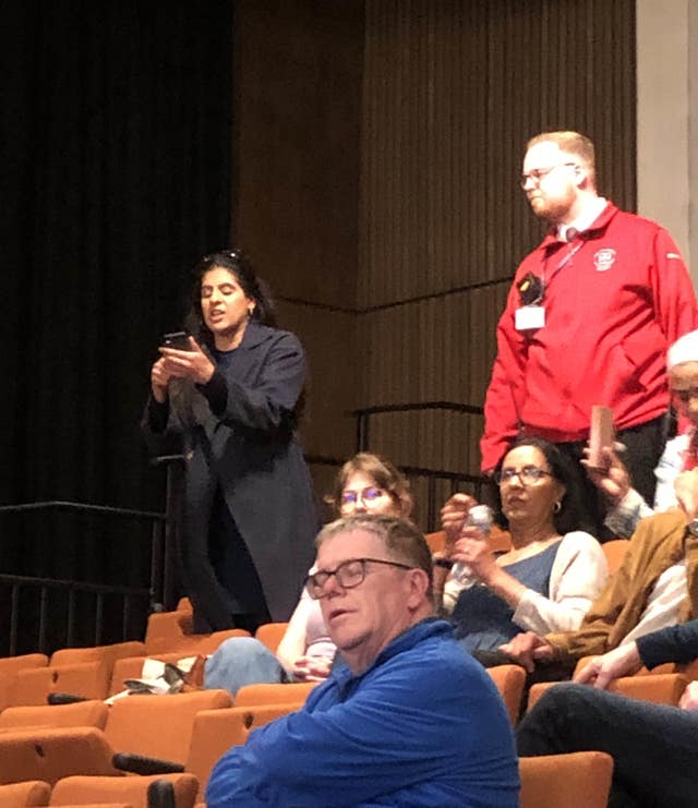 Woman standing up and shouting at someone out of frame