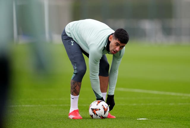 Cristian Romero bends over and puts his hand on the ball during a training session