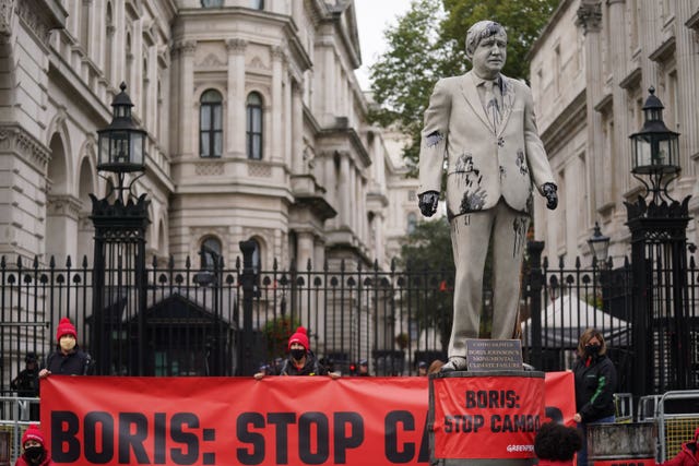 Greenpeace demonstrators outside Downing Street with a statue of Prime Minister Boris Johnson splattered with oil (Victoria Jones/PA)