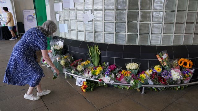 A woman leaves flowers outside Perivale Tesco, Greenford, where 87-year-old Thomas O’Halloran used to play his accordion 