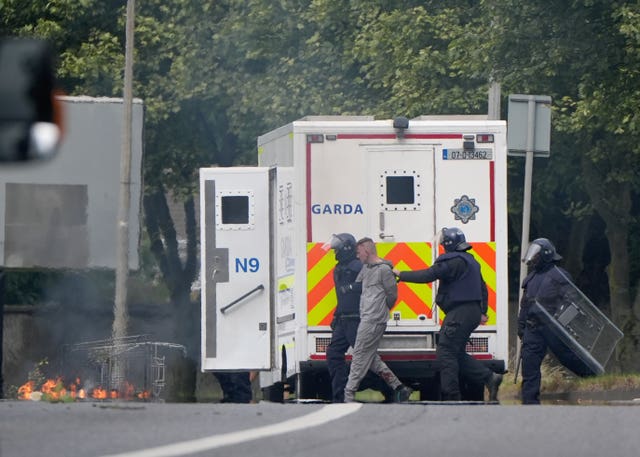 Two men take a protester to a Garda van