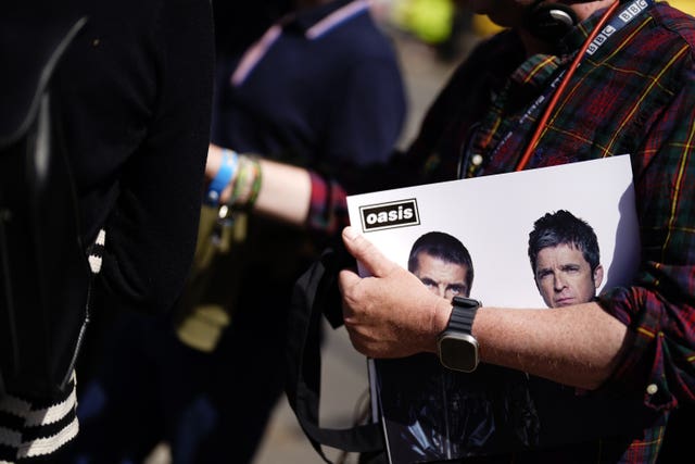 An Oasis fan holds a copy of the souvenir tour programme 